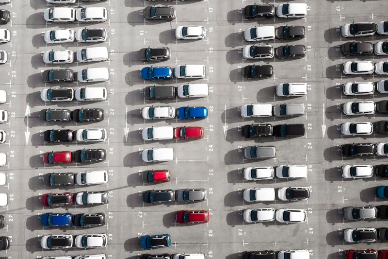 Vogelperspektive auf einen großen Parkplatz bei Gebrauchtwagen Ankauf Stade, der mit Reihen weißer Autos gefüllt ist.